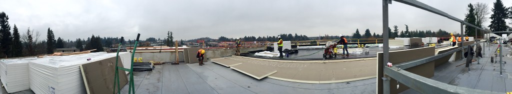 Large roofing project under construction, roofers laying down insulation.