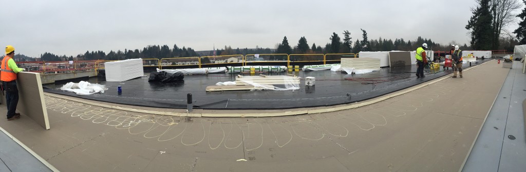 Large roofing project under construction, roofers laying down insulation.