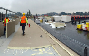 Large roofing project under construction, roofers laying down insulation.