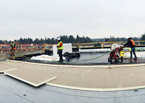 Three roofers form Stanley Roofing work atop a roof.