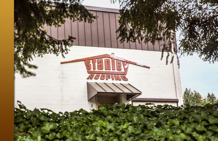 Brick building with large "Stanley Roofing" sign above the entrance.