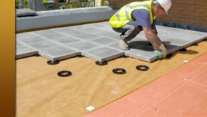Roofing technician lays tile on a roof under construction.